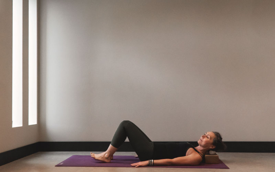 woman Laying on yoga mat doing yoga - Kind Living - Orillia