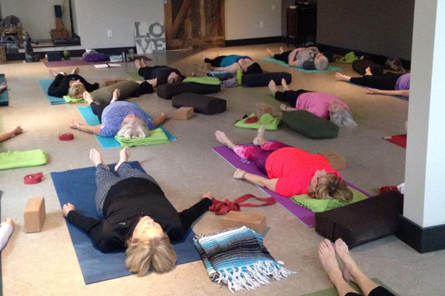 Women participating in a Yoga class, laying down in Savasana